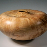 A wooden bowl with a hole in the middle of it.